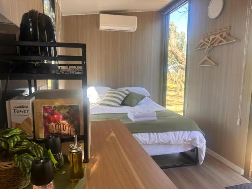 a bedroom with a bed and a desk with a window at Tallarook Hilltop Tiny House 2 by Tiny Away in Tallarook