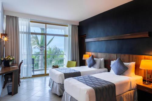 a hotel room with two beds and a window at Giraffe Beach Hotel in Dar es Salaam