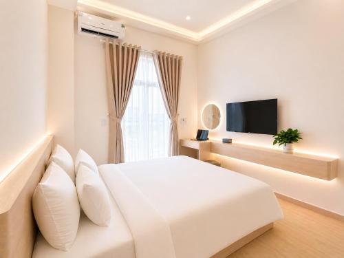 a white bedroom with a bed and a television at Amory Airport Hotel in Ho Chi Minh City