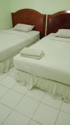 two beds sitting next to each other in a room at Hotel Mayang Sari 2 in Jambi
