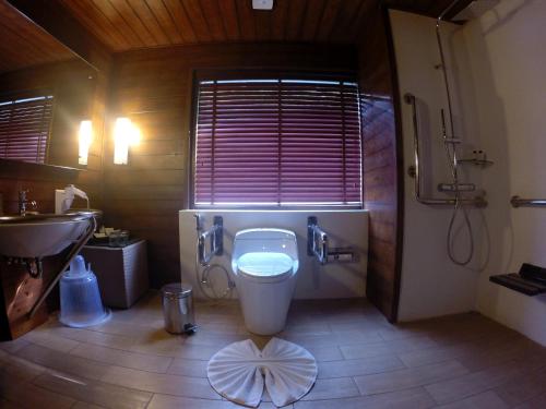 a bathroom with a toilet and a sink and a window at The Tamara Coorg in Kakkabe