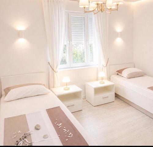 a white bedroom with two beds and a window at Relax Villa with Pool in Bihać