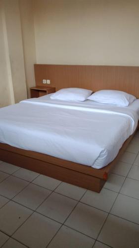 a bed with white sheets and pillows in a room at Hotel Mayang Sari 2 in Jambi