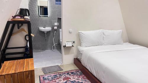 a bedroom with a bed and a bathroom with a sink at Arjuna Hill in Sumberbrantas