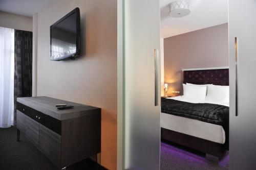 a bedroom with a bed and a tv on the wall at Hotel 3 Trio in Białystok