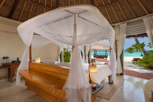 a bedroom with a canopy bed with a view of the ocean at Banyan Tree Vabbinfaru in Male City