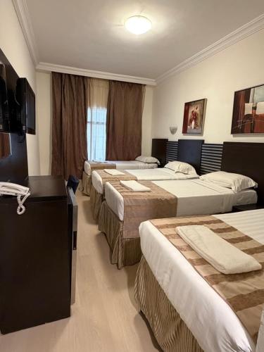 a hotel room with four beds in a row at Miaad Al Majd Hotel in Mecca