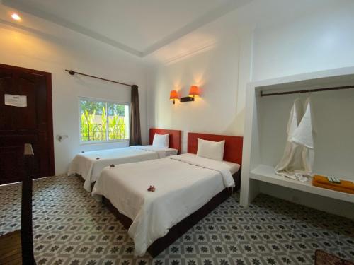 two beds in a room with a window at STC Hotel School in Phumĭ Réach Born (1)