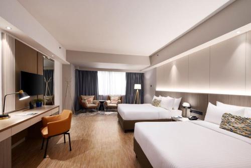 a hotel room with two beds and a desk at RELC International Hotel in Singapore