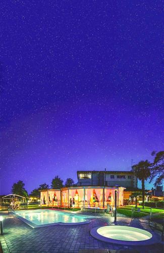 a building with a swimming pool at night at Villa Riviera Hotel Udine in Pradamano
