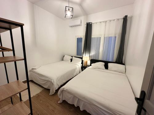 two beds in a small room with a window at Urban Loft Dakar by Immo Kit BNB in Dakar