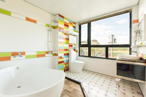 a bathroom with a tub and a toilet and a window at Melinda Resort in Hengchun