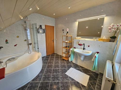 a bathroom with a tub and a sink at Haus Herdi-Schön in Herdwangen-Schönach