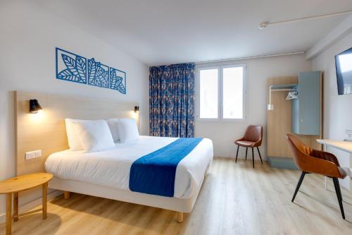 a hotel room with a bed and a desk at Karaez Hôtel - BritHotel Carhaix in Carhaix-Plouguer