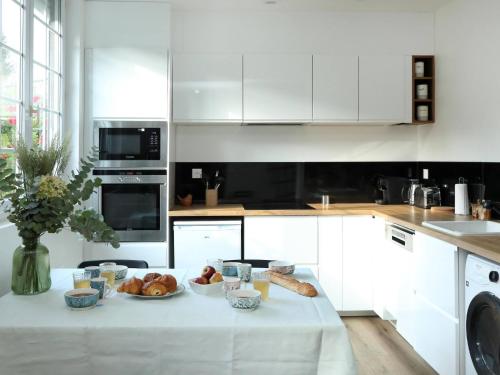 a white kitchen with a table with food on it at Suite des Princes with Private Garden by La Boîte En Plus in Chantilly