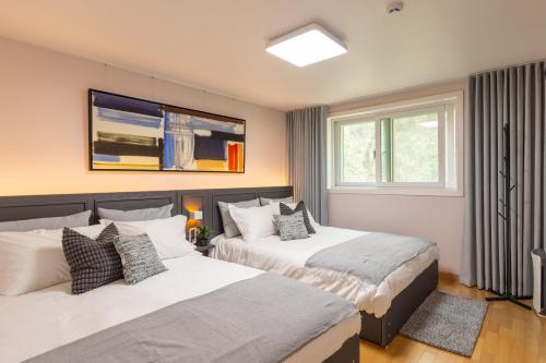 two beds in a room with two windows at 스테이 한집 in Suwon