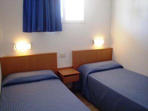 twee bedden in een kleine kamer met blauwe lakens bij Apartamentos Karina in Playa del Inglés