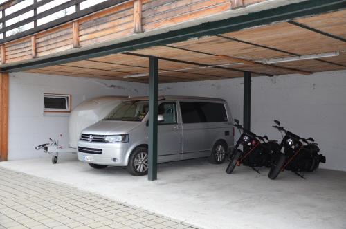 a van parked in a garage with two motorcycles at Pension zum Schreiner in Hermagor