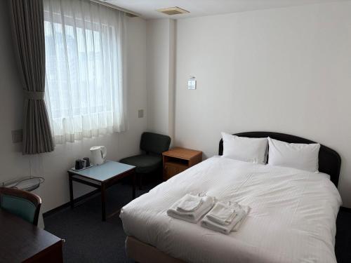 ein Hotelzimmer mit einem Bett, auf dem zwei Handtücher liegen in der Unterkunft Hotel Green Arbor in Sendai