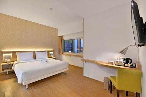 a bedroom with a bed and a desk and a television at Whiz Prime Hotel Basuki Rahmat Malang in Malang