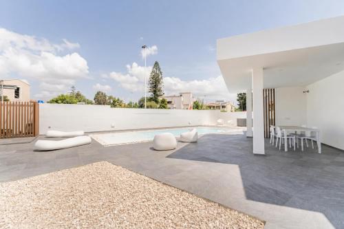 a patio with white furniture and a white wall at Leonida's Home - Shared Pool, Jacuzzi and beach 150mt in Su Forti