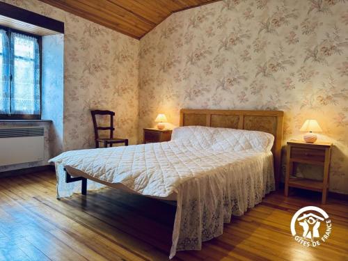 a bedroom with a bed and two tables and a chair at Le gîte de cals haut in Lacombe