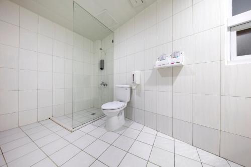 a white tiled bathroom with a toilet and a shower at Tomorrow Hotel in Taipei