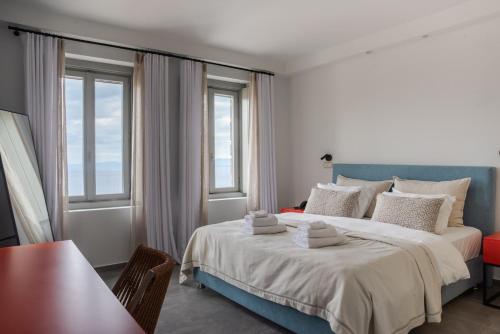a bedroom with a large bed and two windows at Sampatiki Suites & Spa - Luxury Seaview Suites - Opened 2024 in Leonidio