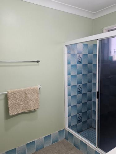a bathroom with a shower with blue tiles at Rockhampton Court Apartment in Rockhampton