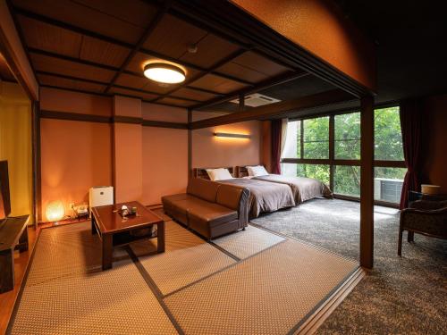 a bedroom with a bed and a couch and a table at Yamaga Onsen Sumi in Yamaga