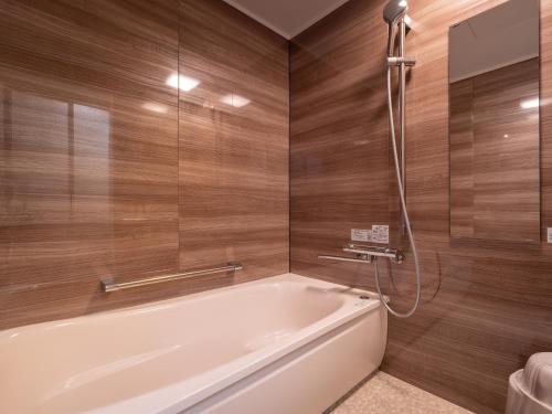 a bathroom with a white tub and wooden walls at Yamaga Onsen Sumi in Yamaga