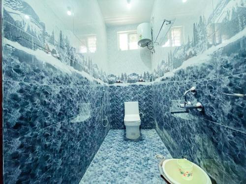 a blue tiled bathroom with a toilet and a sink at The Storyhouse in Kūkkāl