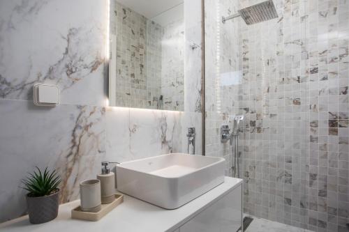a white bathroom with a sink and a shower at Calma Luxury Villas in Kolymbia