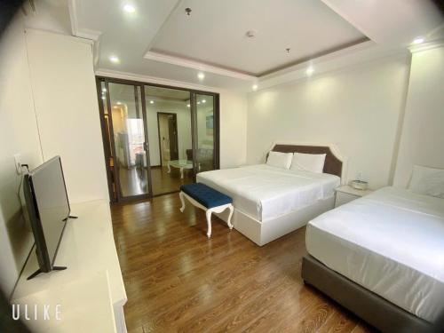 a bedroom with two beds and a flat screen tv at Khách sạn QUEENIE in Hai Phong