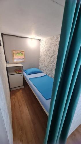 a small bed in a small room with blue curtains at Hostel Caps Home in Astana