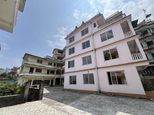 a large white building with windows on a street at Subhechchha Hotel in Charikot