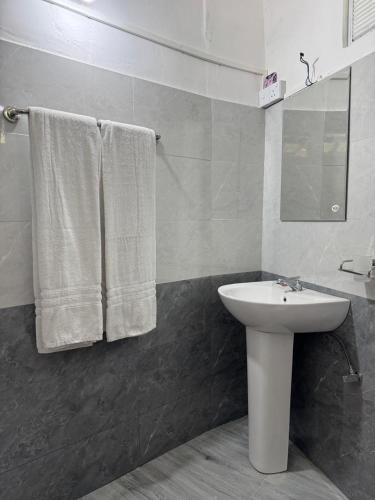 a bathroom with a sink and a mirror and towels at The Tamarind Villa in Kandy