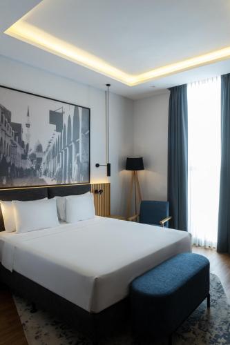 ein Schlafzimmer mit einem großen weißen Bett und einem blauen Stuhl in der Unterkunft Radisson Hotel Madinah in Medina