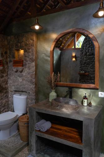 a bathroom with a sink and a toilet and a mirror at The Salty Jungle in Cijulang Nusawiru Airport