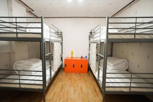 a room with three bunk beds and a orange table at Suncheon Namu Guesthouse in Suncheon