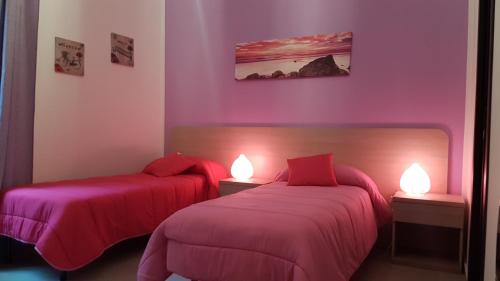 1 dormitorio con 2 camas con sábanas rosas y luces en Buonaluna B&B, en Palermo