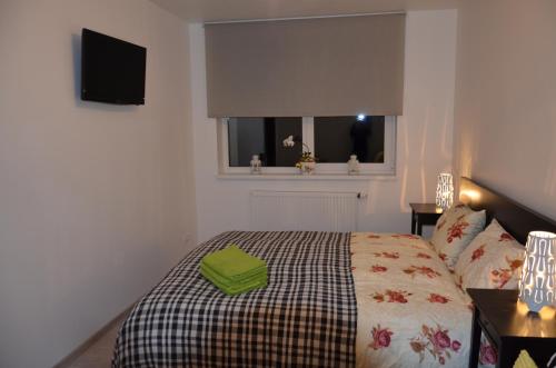 a bedroom with a bed with a green towel on it at Apartments Ozo Park in Vilnius