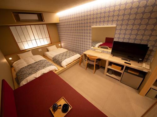 a small room with two beds and a desk with a television at Sunriver Oboke in Miyoshi