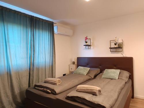 a large bed in a room with a large window at B23 Apartman in Harkány