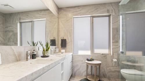 a white bathroom with two sinks and a toilet at The Coral Esplanade in Mornington