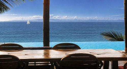 a wooden table with chairs and a sailboat in the ocean at Villa Jacuzzi Seaview Villa in Chaweng Noi Beach