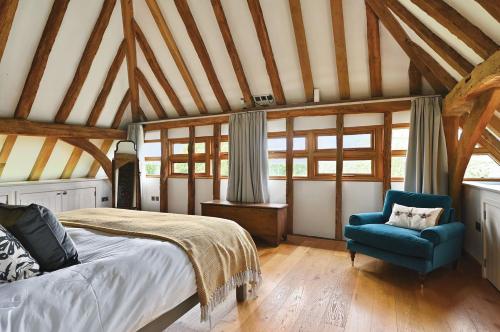 a bedroom with a bed and a blue chair at The Manor Barn in Canterbury