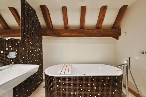 a bathroom with a white tub and a sink at The Manor Barn in Canterbury