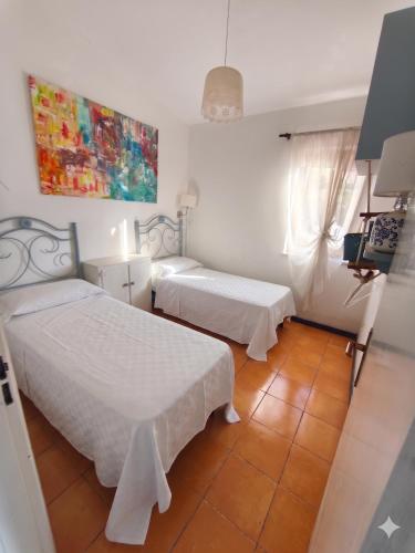 a bedroom with two beds and a painting on the wall at La casita in Capo Vaticano