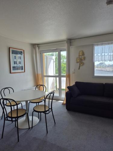 a living room with a table and chairs and a couch at Studio avec balcon, 4 personnes in Quiberon